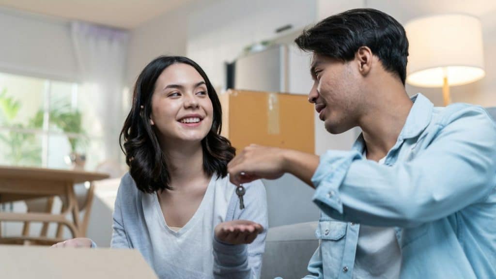 A young woman is given a set of keys by a man while sitting inside a home.