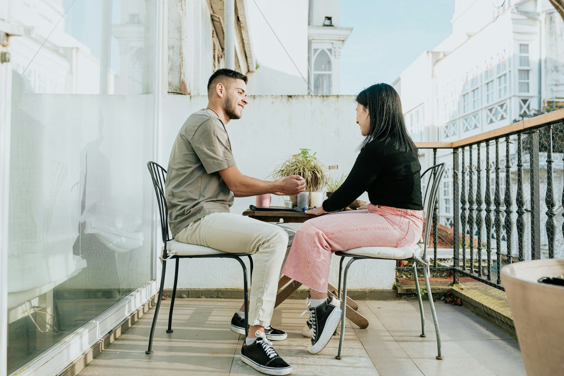 A man and a woman sitting at a table on the balcony.