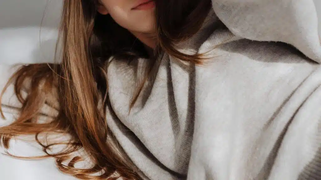 A woman lying down in a cozy sweater with her hair spread out.