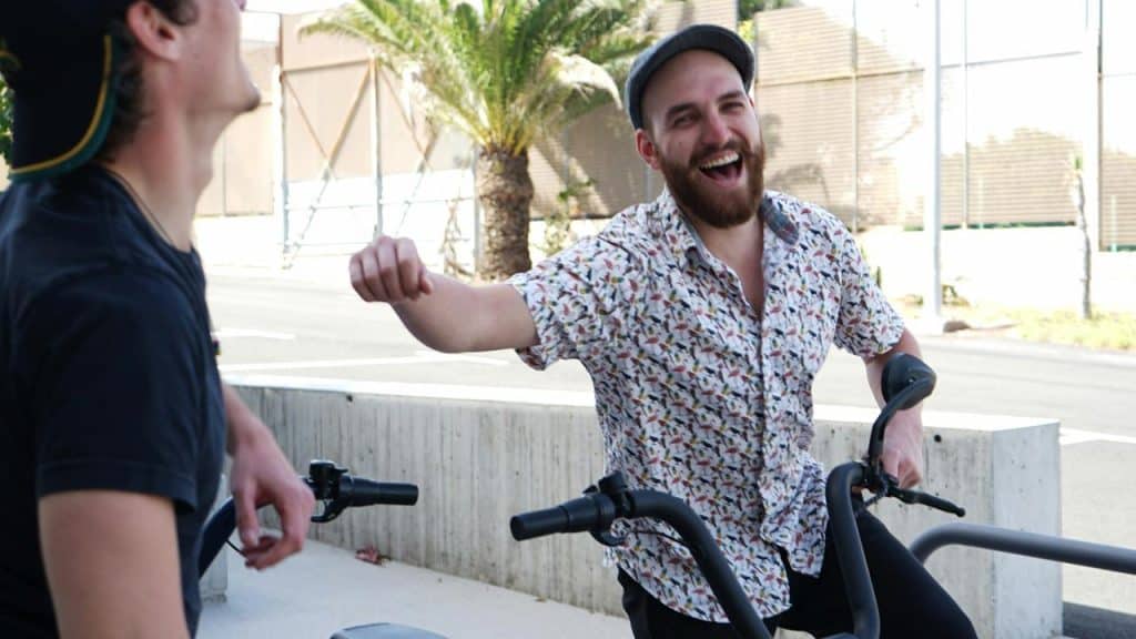 A person laughing while chatting next to a bike outdoors.