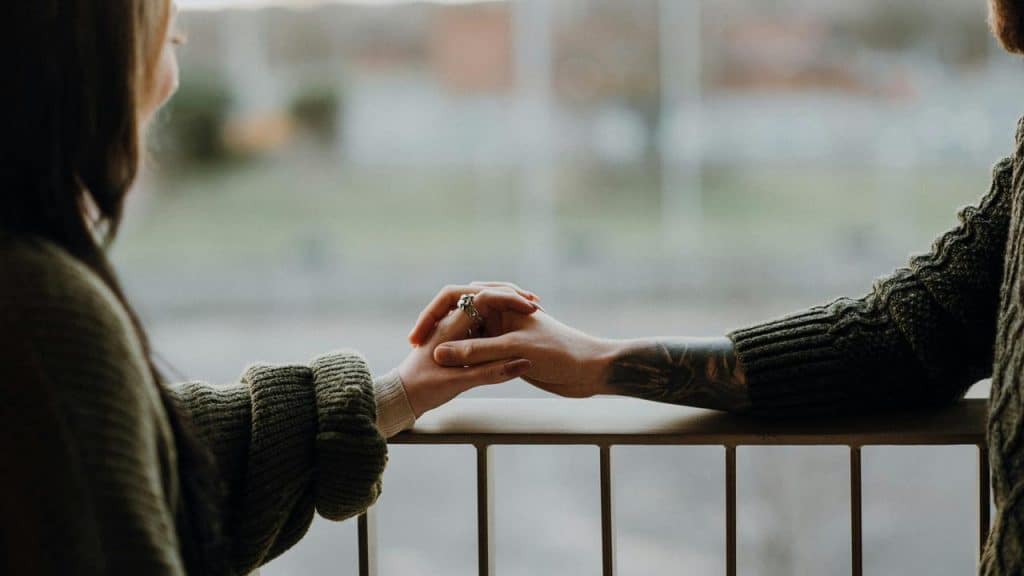 A couple holding hands while standing by a railing.