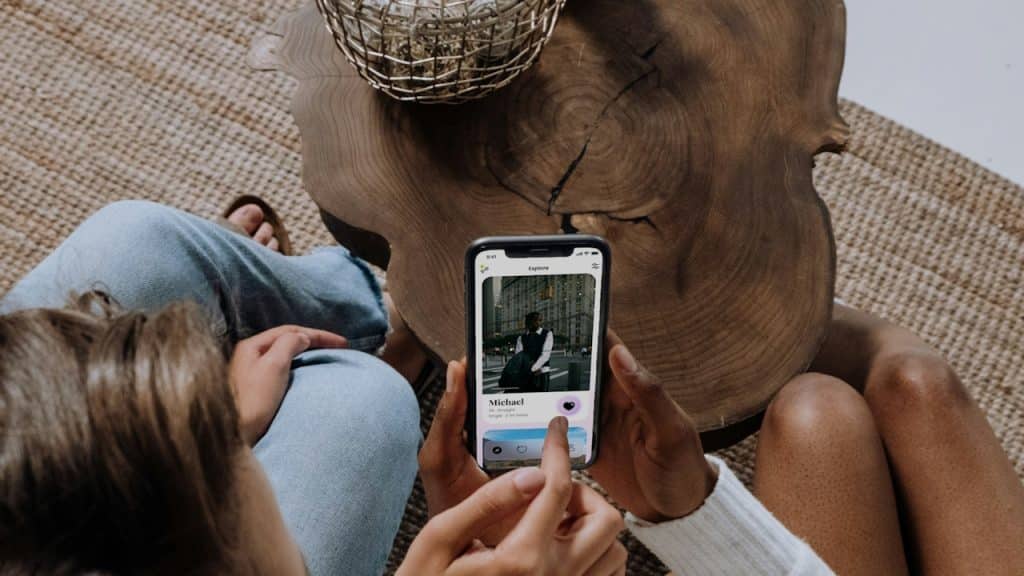 Two people sitting on a couch looking at a cell phone.