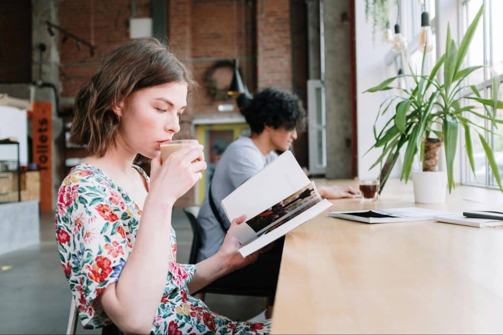 A woman busy with her book and a man busy working beside her