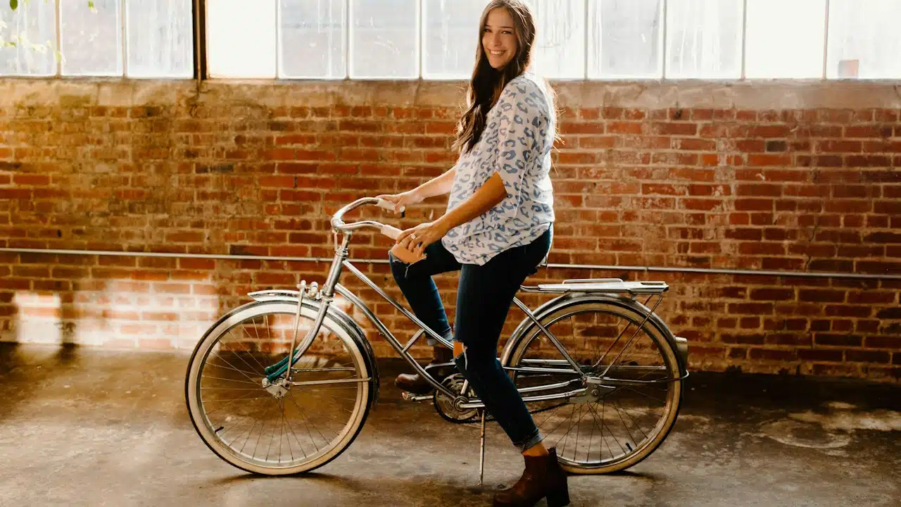 A woman in a long-sleeve white and black floral shirt riding on a bicycle.