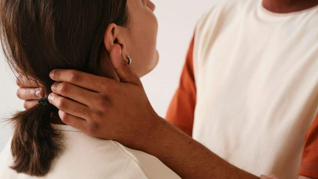 A close-up of a man's arm around a woman's neck and back of the head.