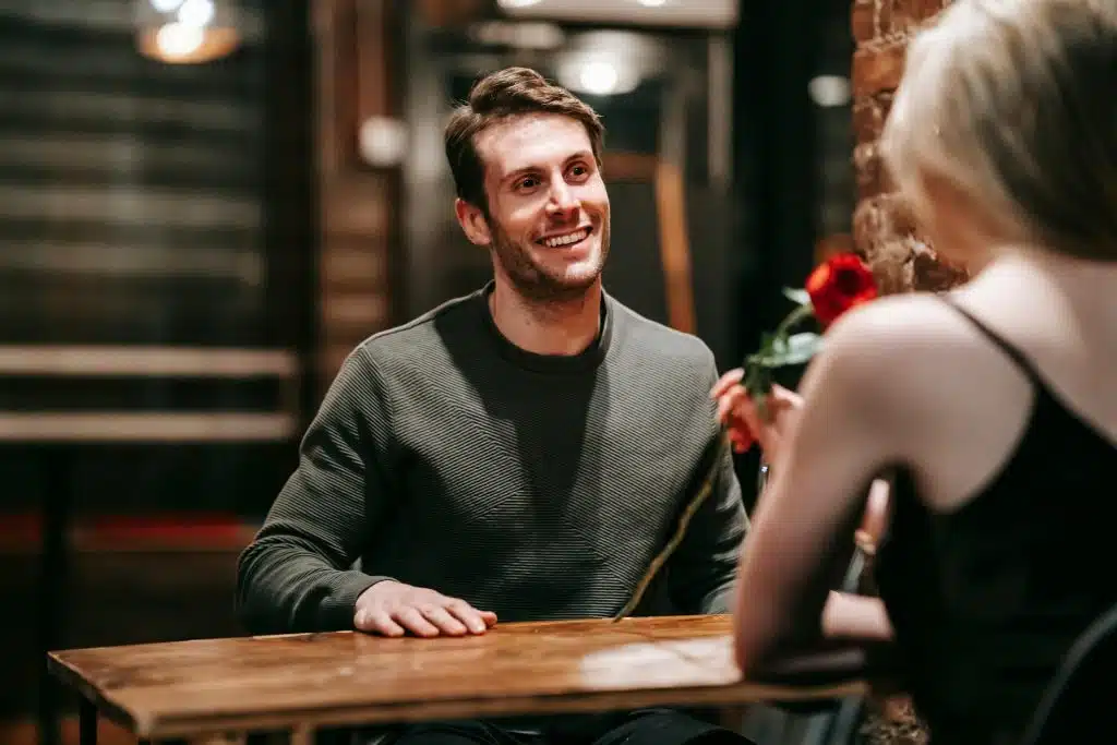 A man looking at the woman holding a rose.