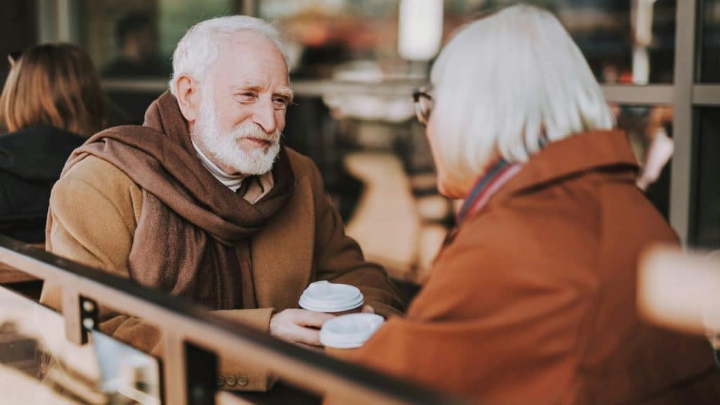 An older couple sitting at a café and enjoying coffee together.