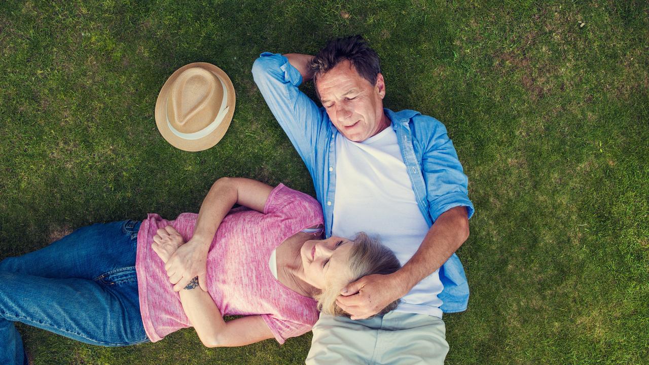 A couple lying on the grass together, relaxing outdoors.
