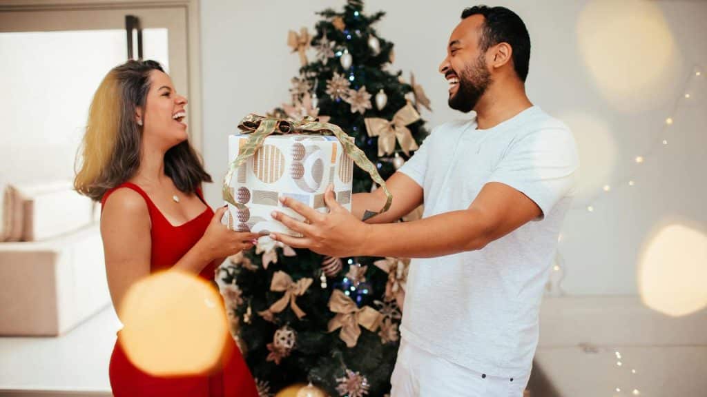 A couple laughing while exchanging gifts.