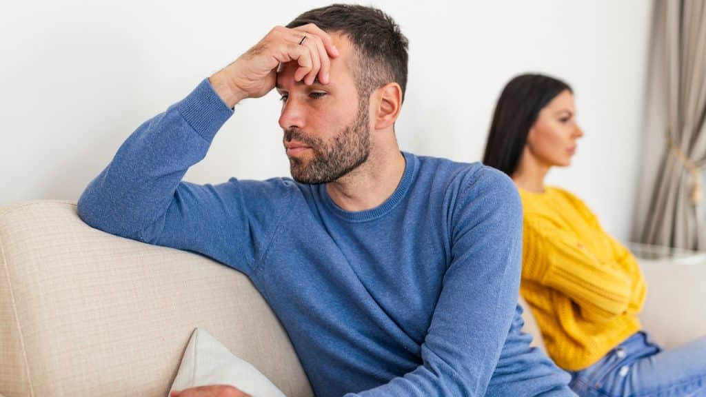 A man and a woman sitting back-to-back after a fight.