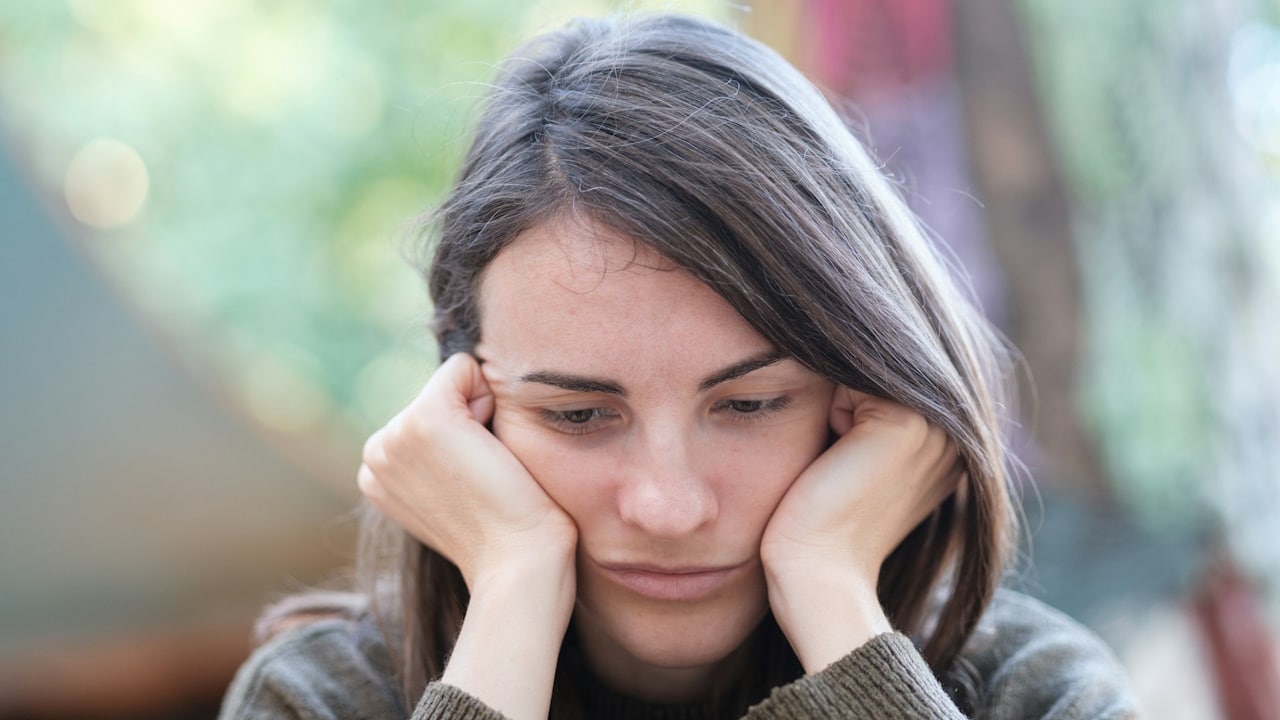 A woman looking upset and holding her face in her hands 