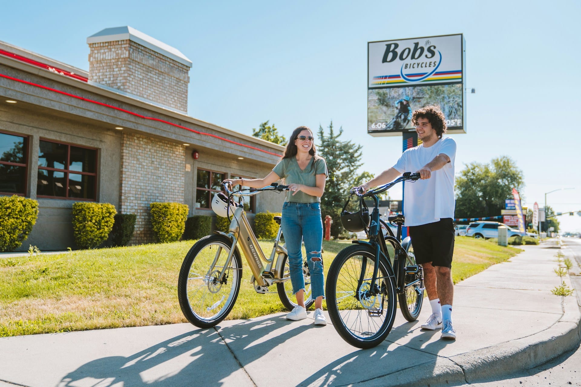 A man and a woman standing on the side of the street with their bikes.