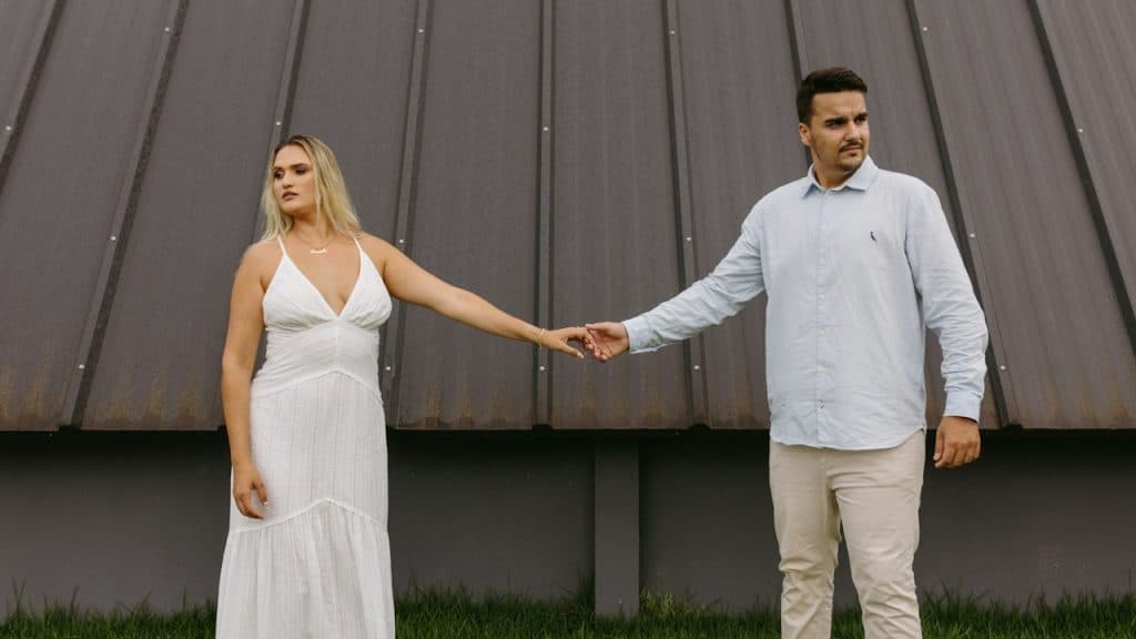 A man and a woman holding hands in front of a building.