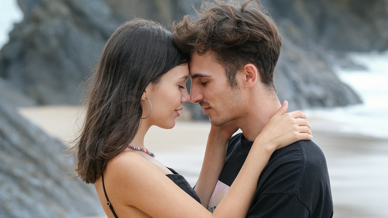 A man and a woman embracing each other on the beach.