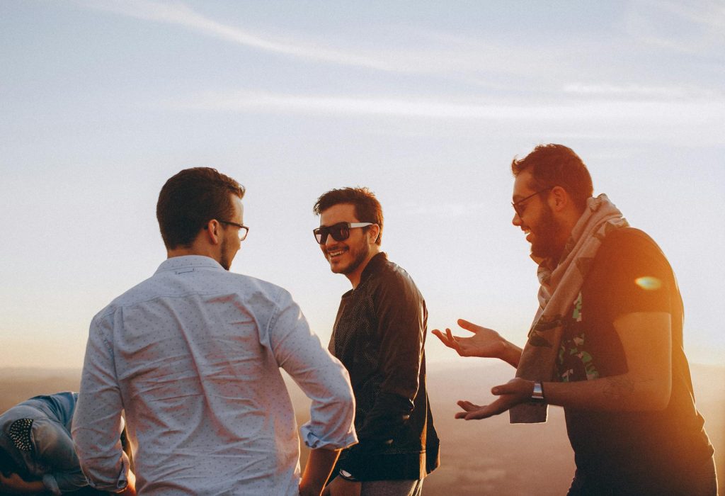 Three men standing outdoors while laughing.