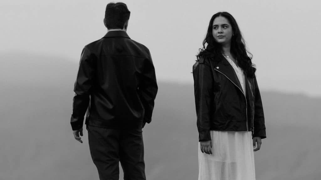 A couple standing with their backs to each other.