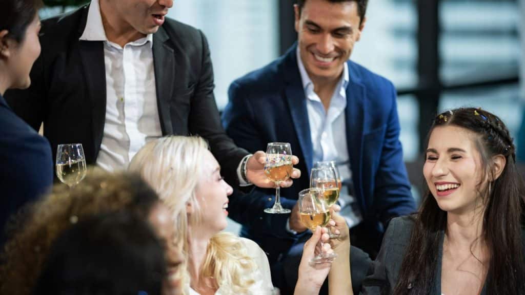 A group of professionals smile and cheer with champagne glasses at a social gathering.
