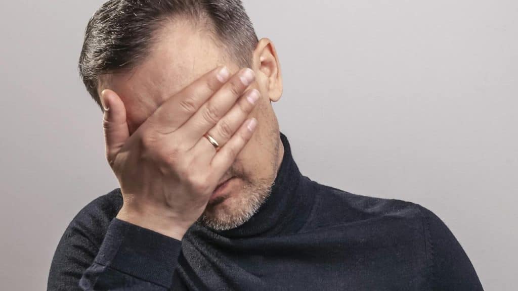 A man covering his face with his hand.