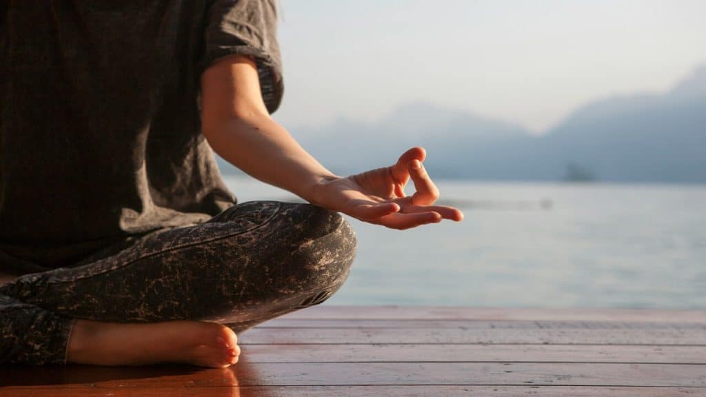 A woman practicing yoga by the lake