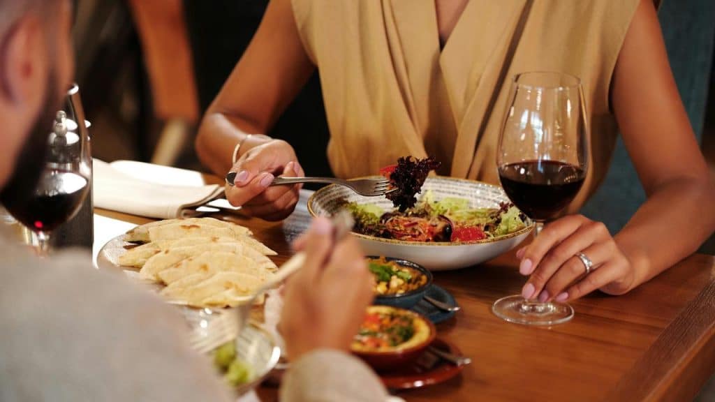 A couple dining at a restaurant with wine and a variety of dishes.