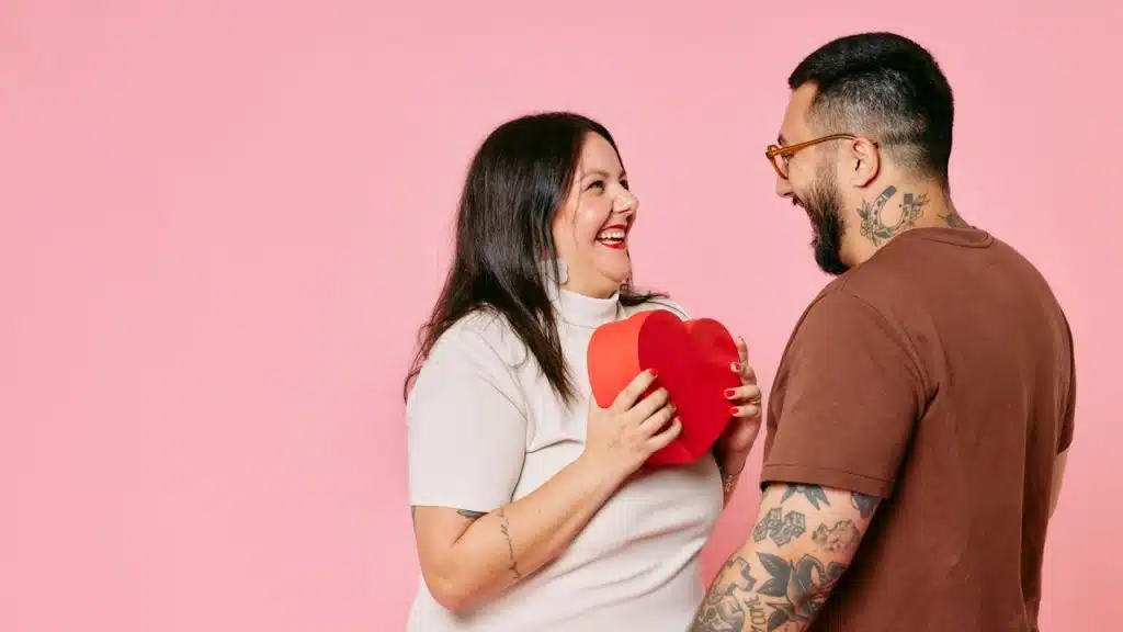 A man holding a heart-shaped box next to a woman.