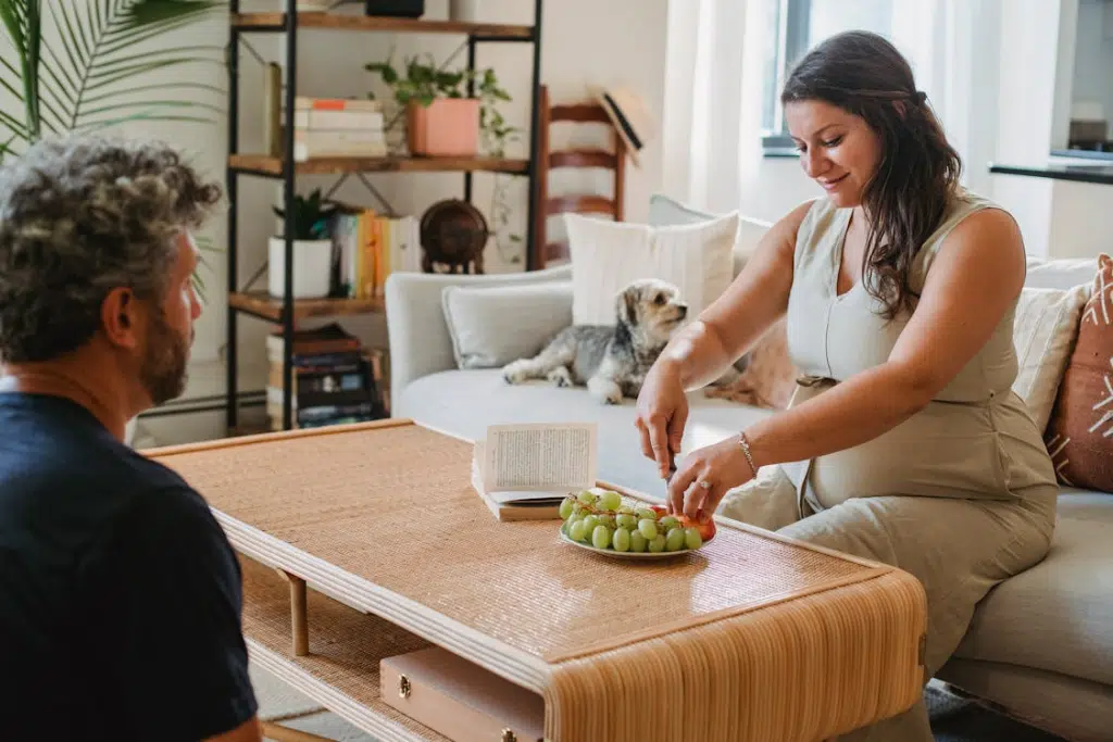 Cheerful pregnant woman serving fruit to a man