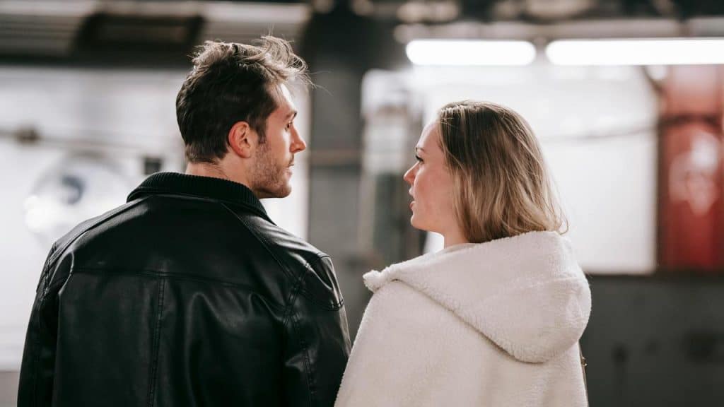 A man and woman standing close together and talking indoors.