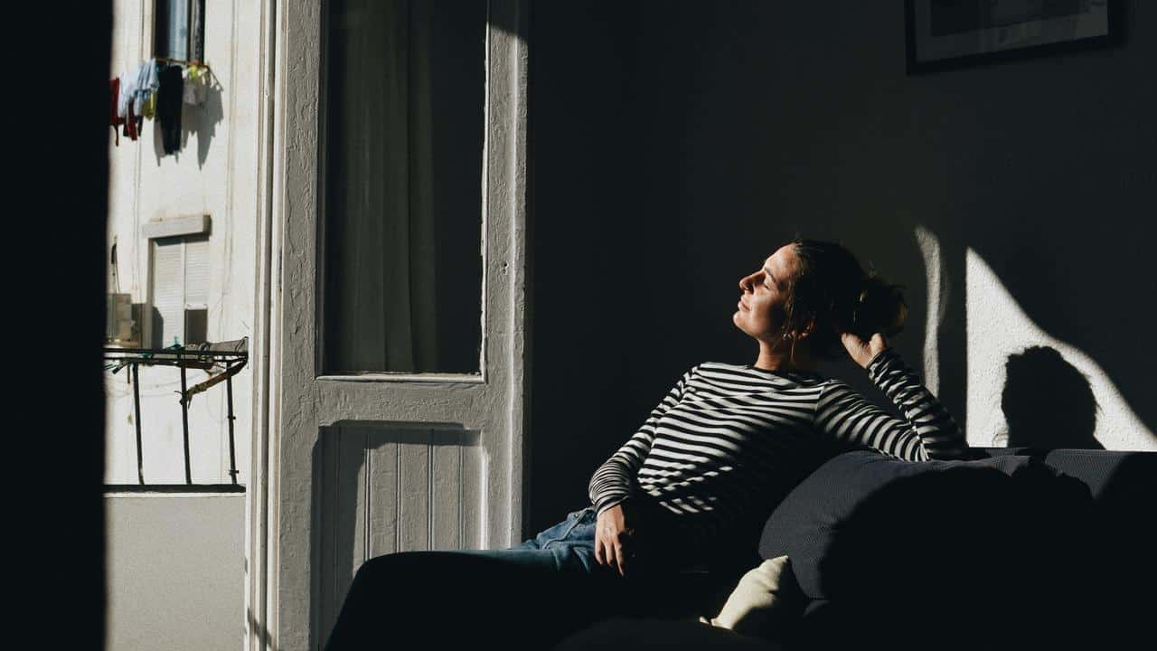 A person reclining on a couch in sunlight.