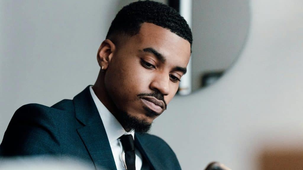 A man in a suit looking down with a thoughtful expression.