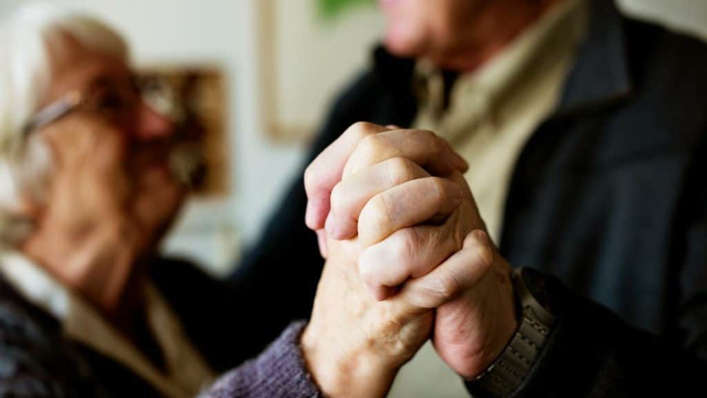 An older couple holding hands closely while dancing.