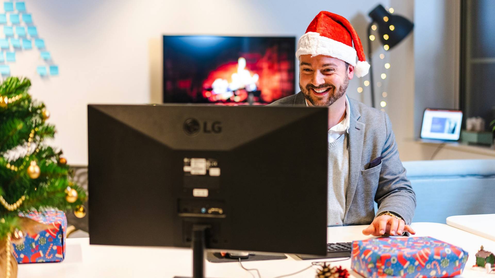 A man wearing a Santa hat working on a computer.