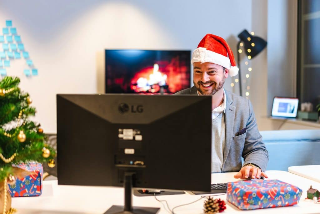 A man wearing a Santa hat working on a computer.