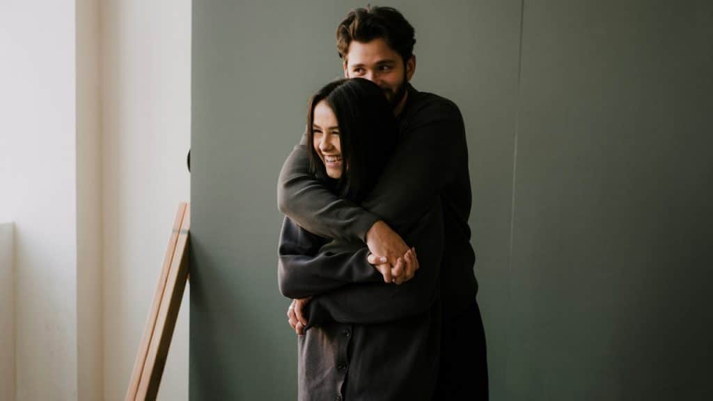 A man hugging her girlfriend from behind.