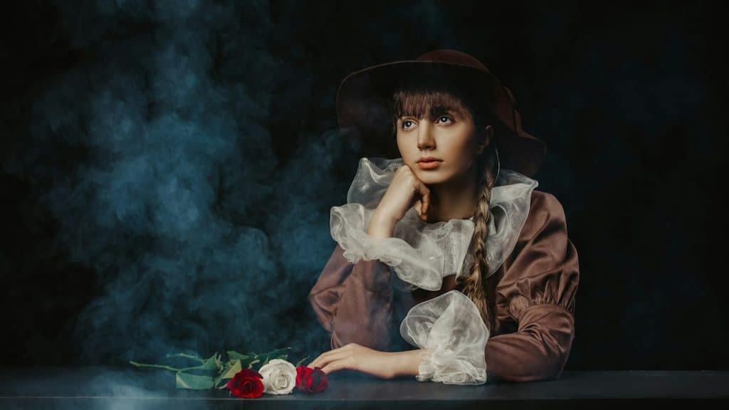 A woman sitting at a table with a rose in her hand.