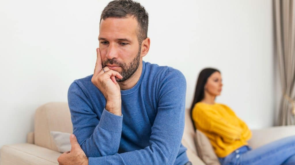 A young couple sitting on a sofa being angry after a fight; a couple having an argument at home.