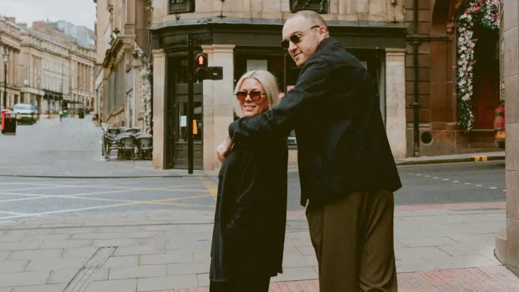 A couple standing on a street in the city.