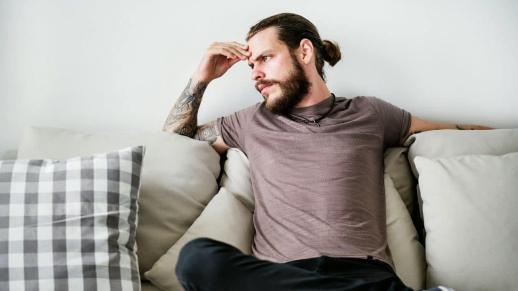 A man with a tattoo is sitting on a couch.