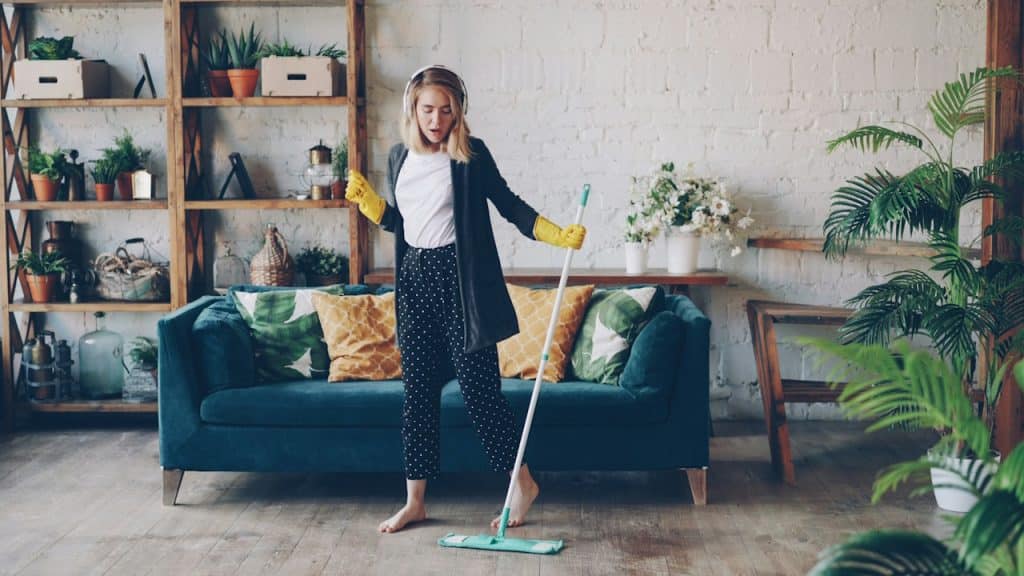 A woman with headphones mopping the house.