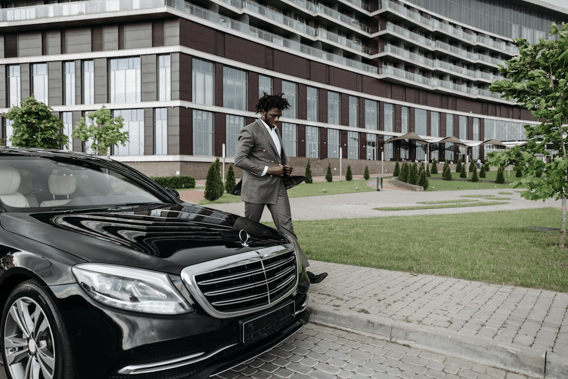 A man walking beside a black car