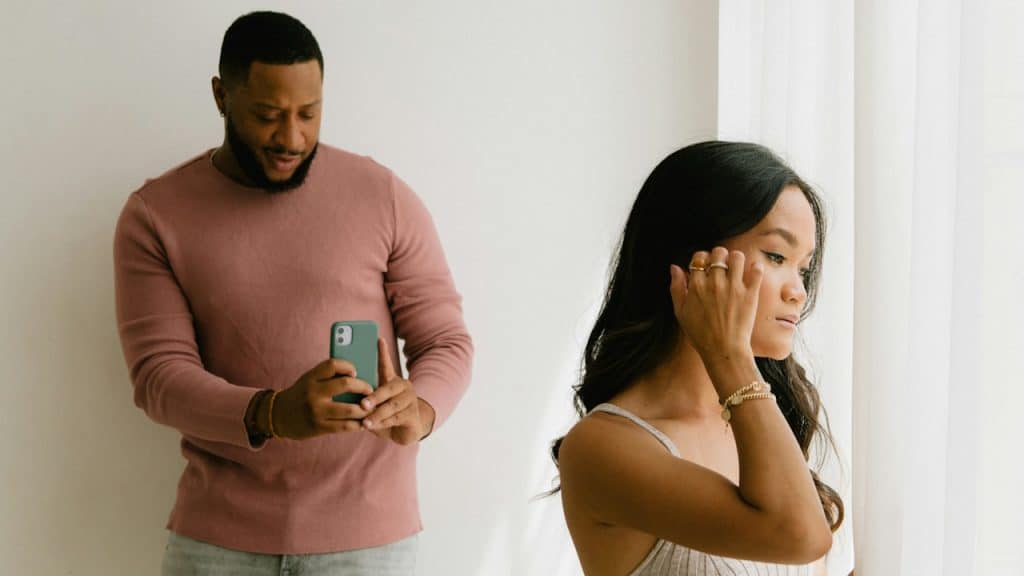 A man is taking a picture of his girlfriend with a cell phone.