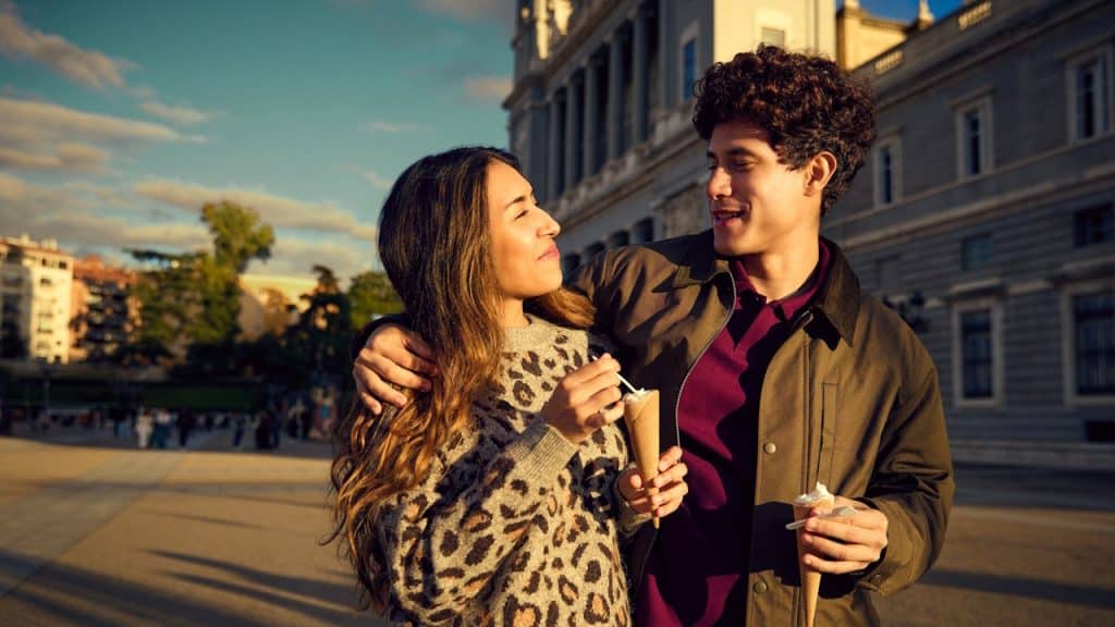 A young couple embracing and eating ice cream outdoors in a city plaza.