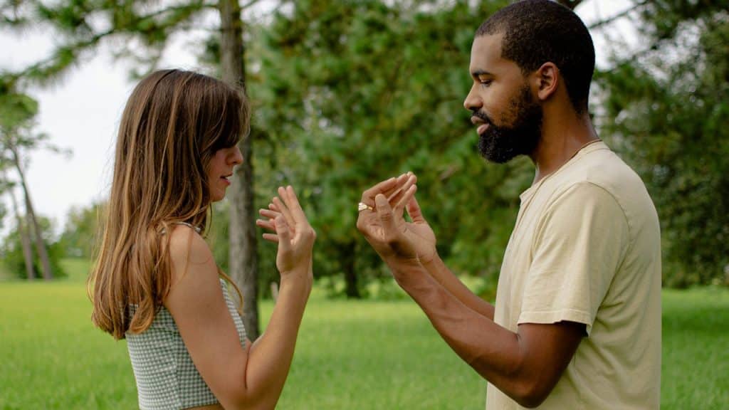 A couple gesturing at each other with their hands.