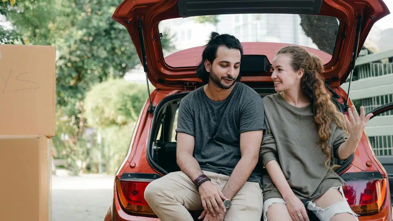 Couple talking while sitting on the car