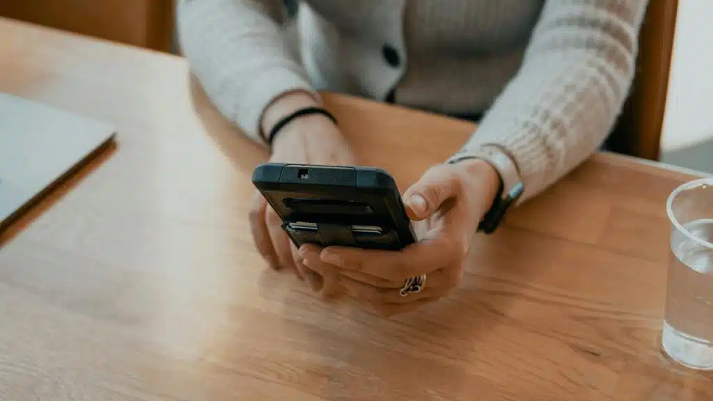 A person sitting at a table holding a smartphone.