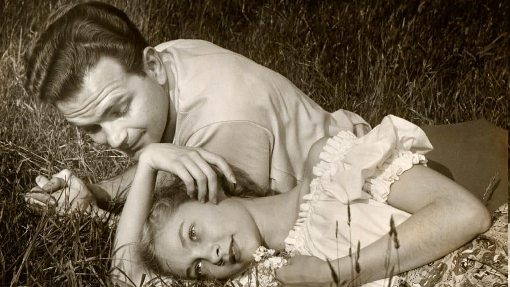 A romantic couple outdoors on grass.