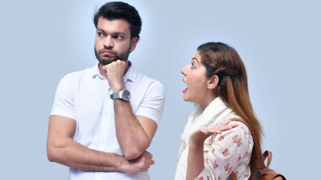 Man in white shirt looking away while a woman shouts and gestures at him.