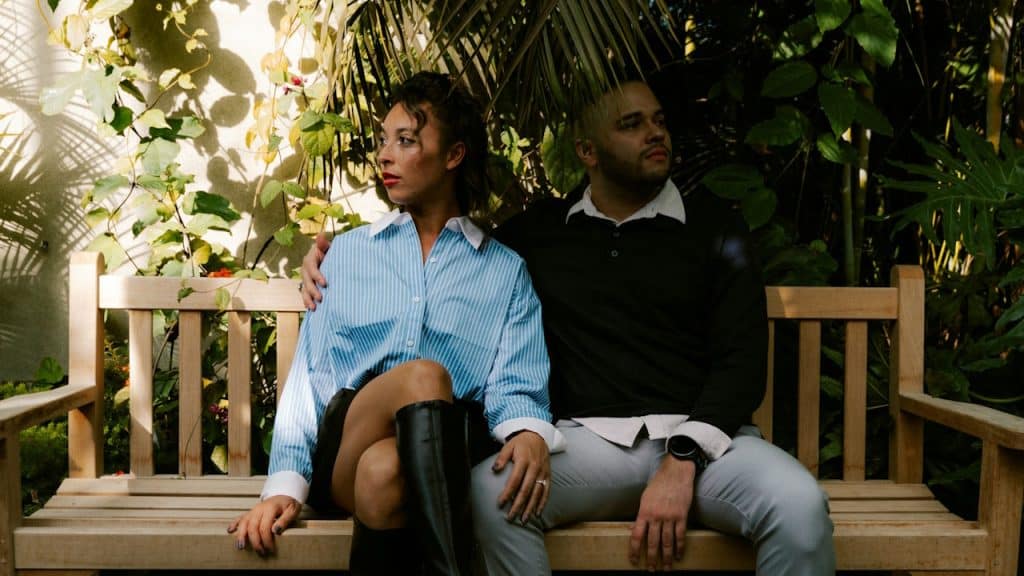 A couple sitting on a wooden bench outdoors.
