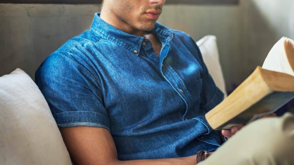 A person sitting on a couch reading a book.