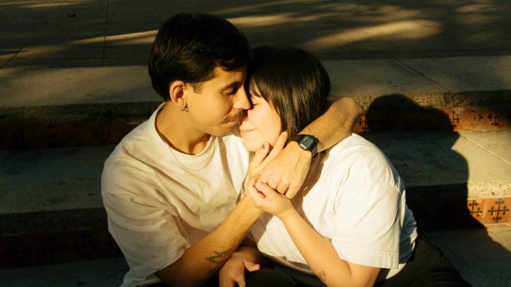 A mustached man holding a woman close.