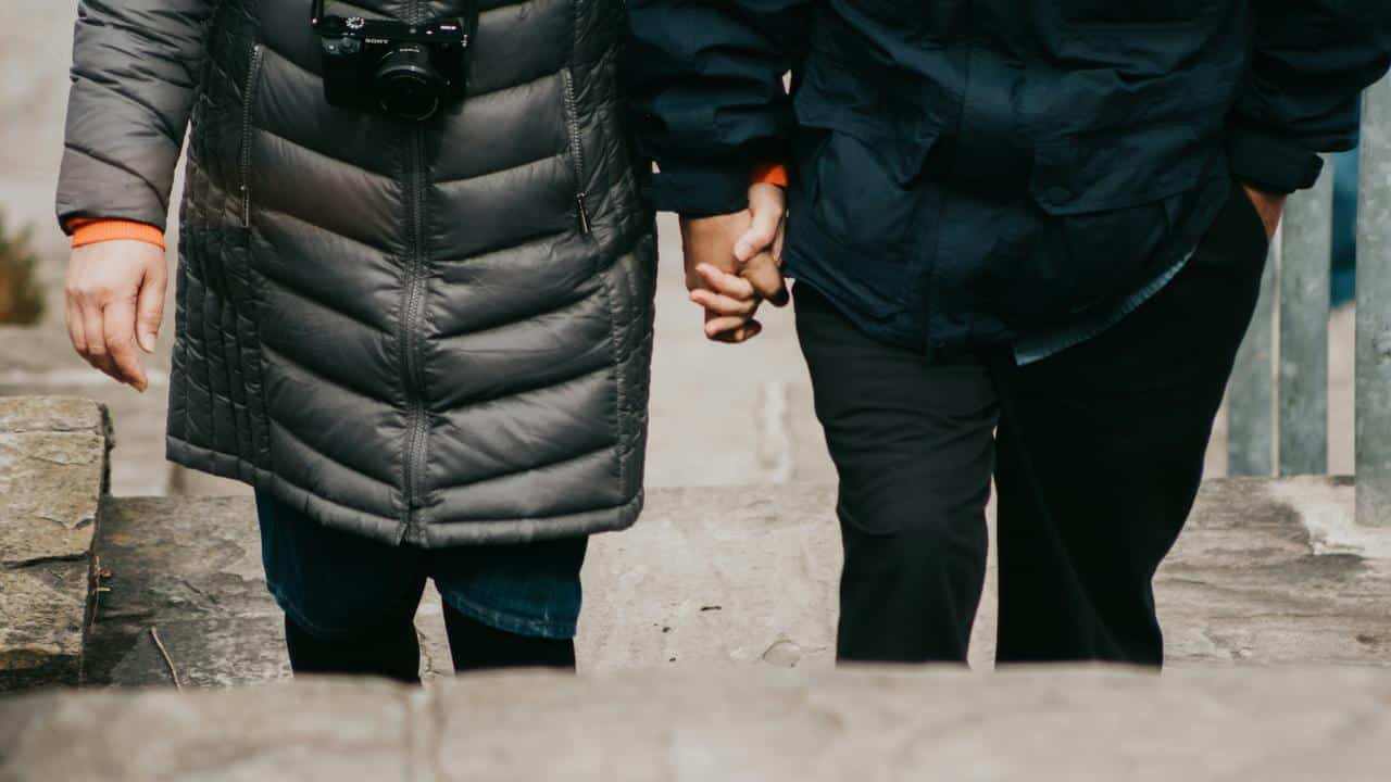 A couple holding hands while walking up stone steps.